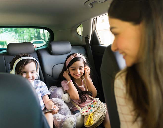 Children wearing headphones in backseat car