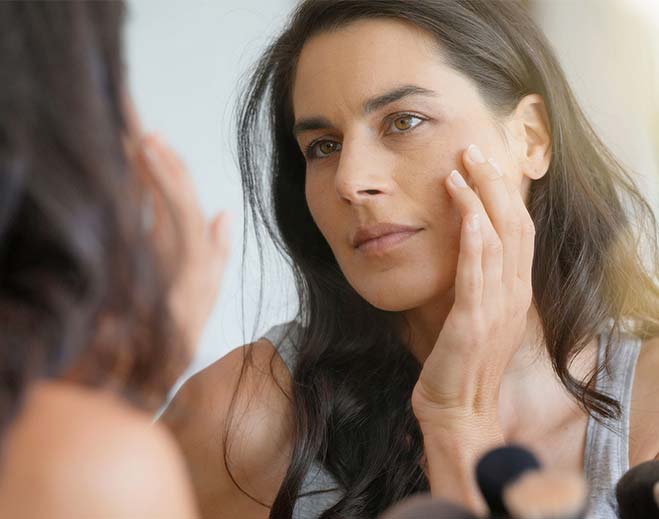 Person examining skin in bathroom mirror